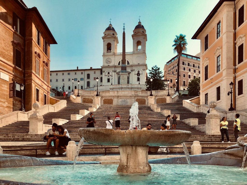 Piazza di Spagna fountain in front of white concrete building during daytime